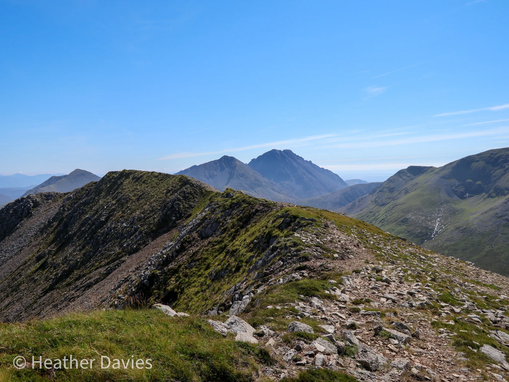 A rocky mountain ridge leading towards the Cuillin peaks beneath a clear blue sky
